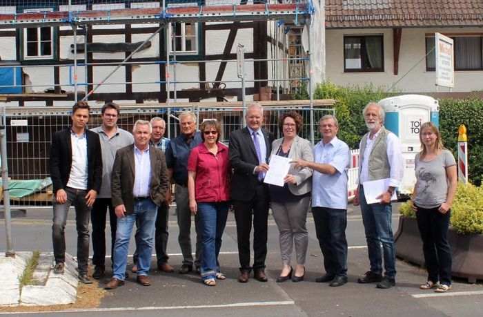Susanne Simmler (Bildmitte) übergibt den Förderbescheid zur Umgestaltung des Dorfplatzes an Bürgermeister Andreas Weiher Übergabe Fördermittelbescheid für Umgestaltung Dalles